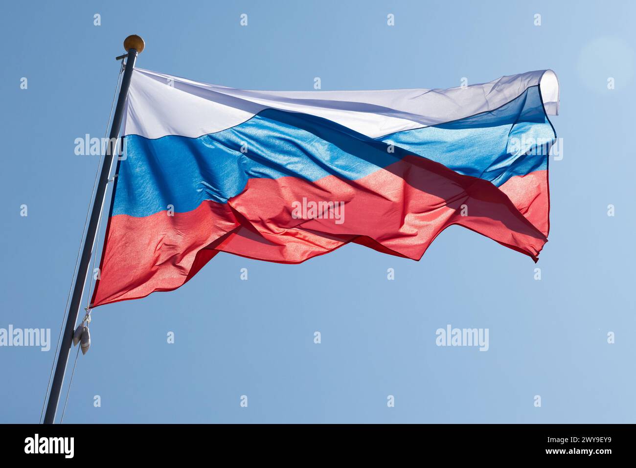The national flag of Russia, also known as the State Flag of the Russian Federation is under bright blue sky on a sunny day Stock Photo