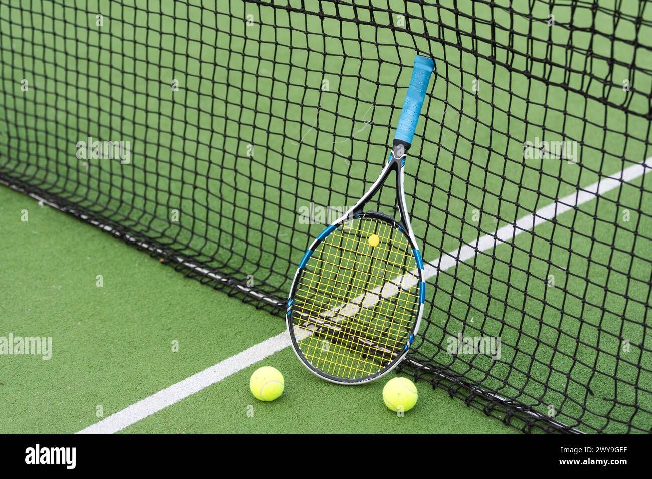 Tennis racket and tennis ball besides the net on outdoor tennis court ...