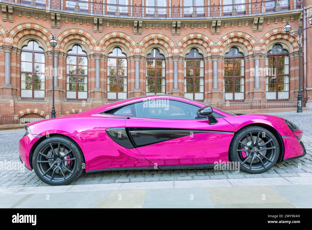 London, UK - May 20, 2023: Pink McLaren 540C supercar in front of St. Pancras Renaissance Hotel Stock Photo