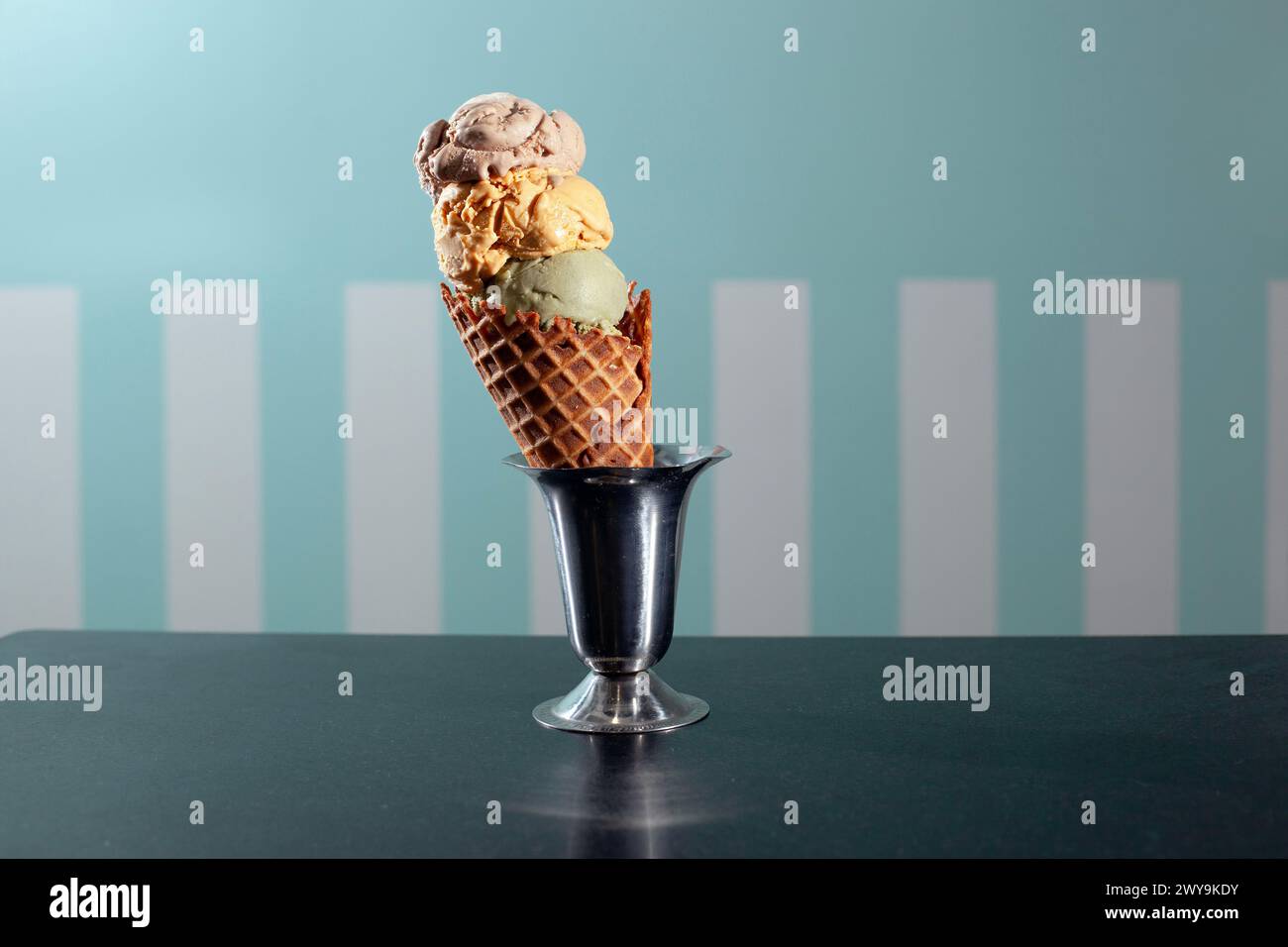 three scoops of ice cream in a waffle cone against striped background ...