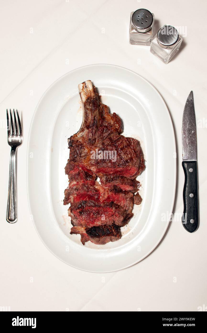 A big steak cut up on a plate with place setting vertical Stock Photo