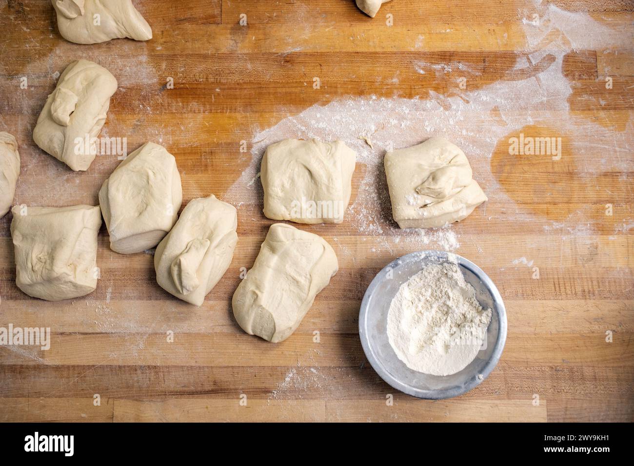 Bread dough separated into portioned loaves on a wood counter Stock Photo