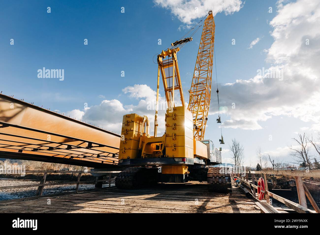 Yellow construction crane atop bridge construction site Stock Photo