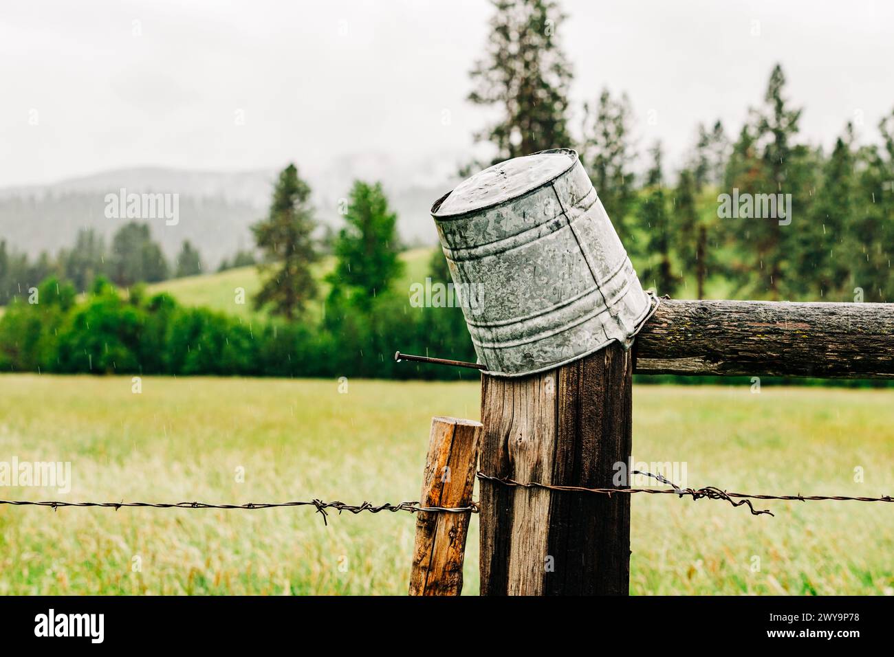 Upside down tin bucket on wood fence in Montana countryside Stock Photo
