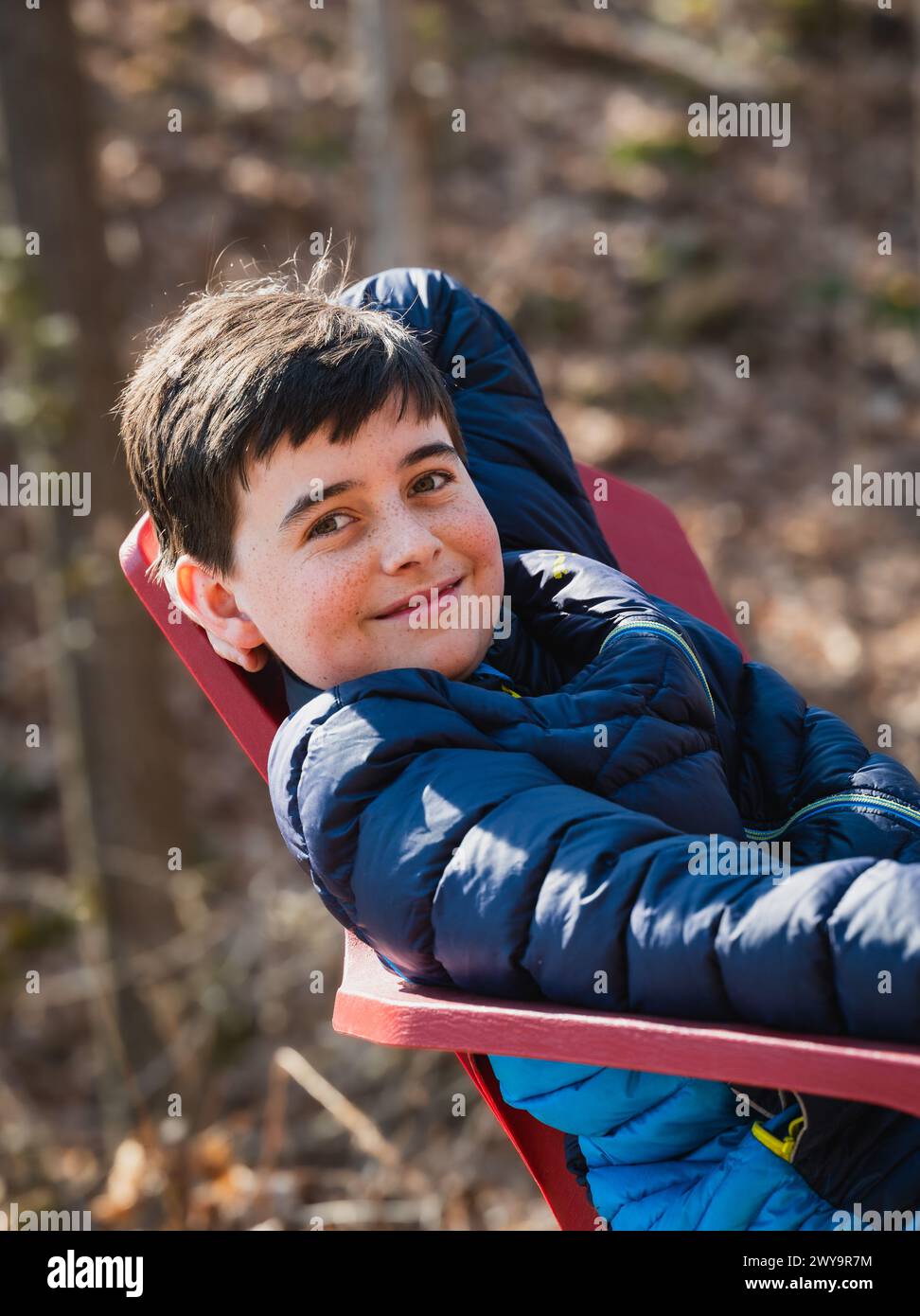 Close up of smiling boy relaxing in a chair outside on a spring day. Stock Photo