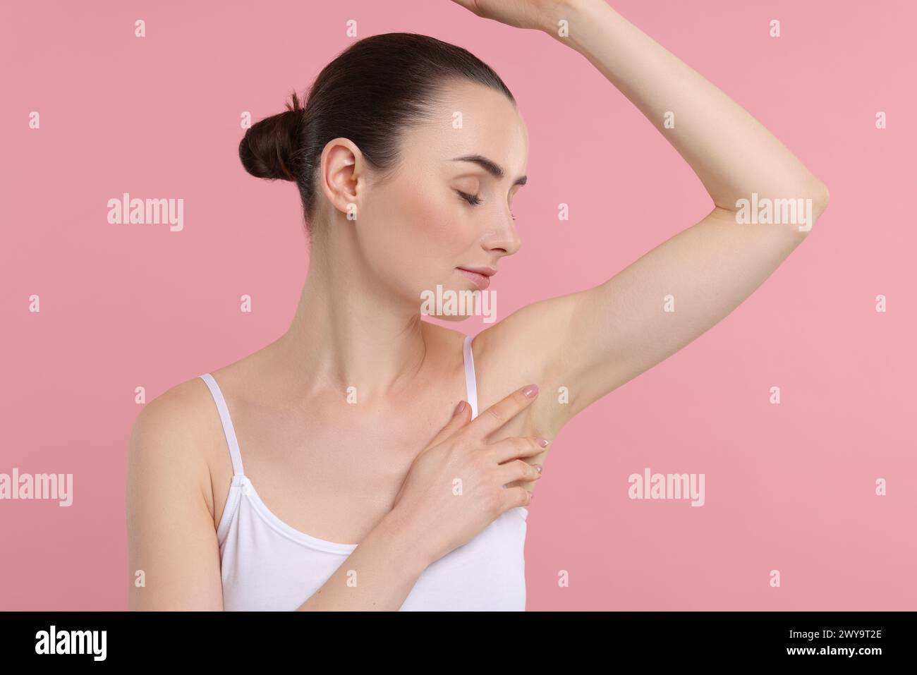 Beautiful woman showing armpit with smooth clean skin on pink background Stock Photo