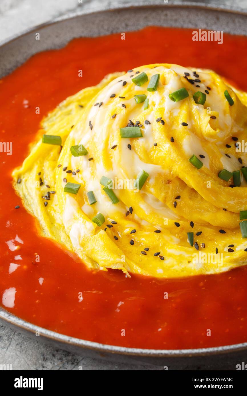 Tornado omelet a Korean dish called a tornado omurice, where a whirlwind of scrambled egg is placed over a mound of rice, and surroun sauce closeup on Stock Photo