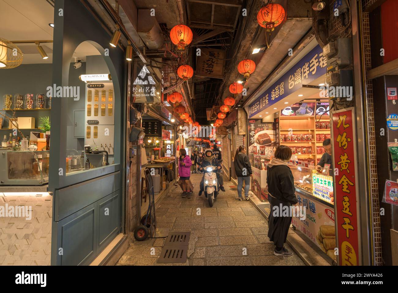 A crowded Jiufen night market lit by red lanterns with shops and people Stock Photo