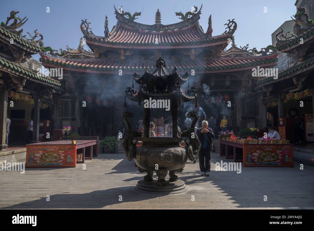 Tranquil scene with an incense burner in the foreground and intricate architecture of the Mazu temple Stock Photo