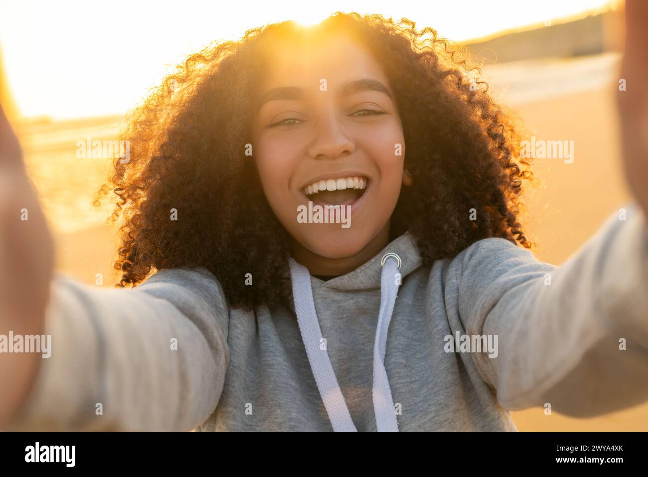 Outdoor portrait of beautiful happy mixed race biracial African American girl teenager female young woman on a beach taking a selfie photograph Stock Photo