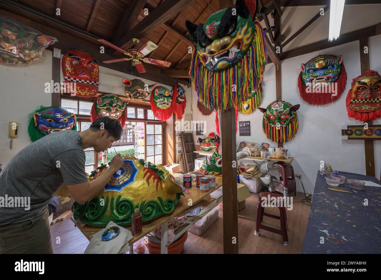 Artisans work on vibrant ceremonial masks in a traditional craft studio in Lukang Stock Photo