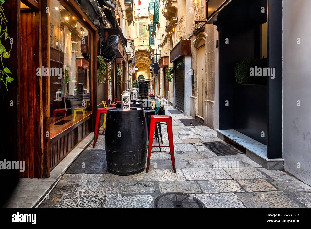 Narrow street with cafes and restaurants in city centre of Valletta, Malta. Stock Photo
