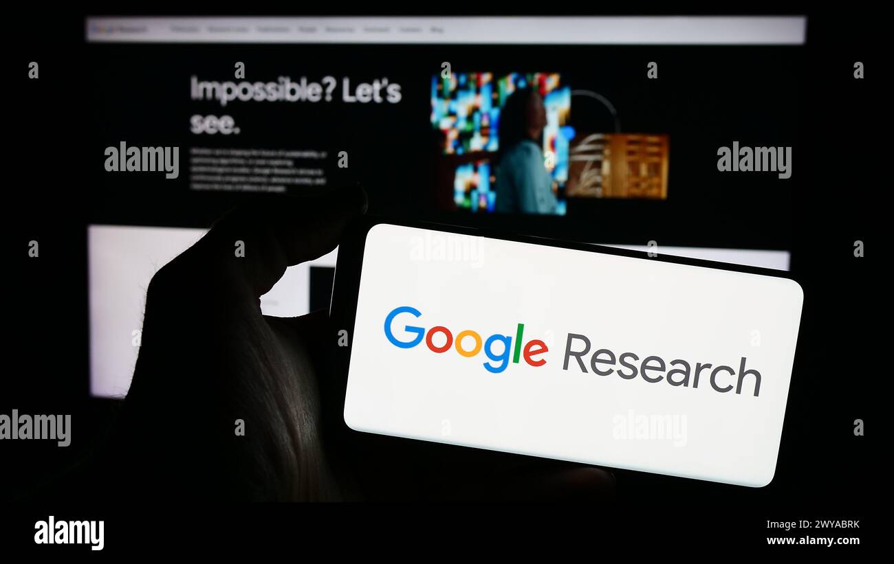 Person holding smartphone with logo of US technology company Google Research in front of website. Focus on phone display. Stock Photo