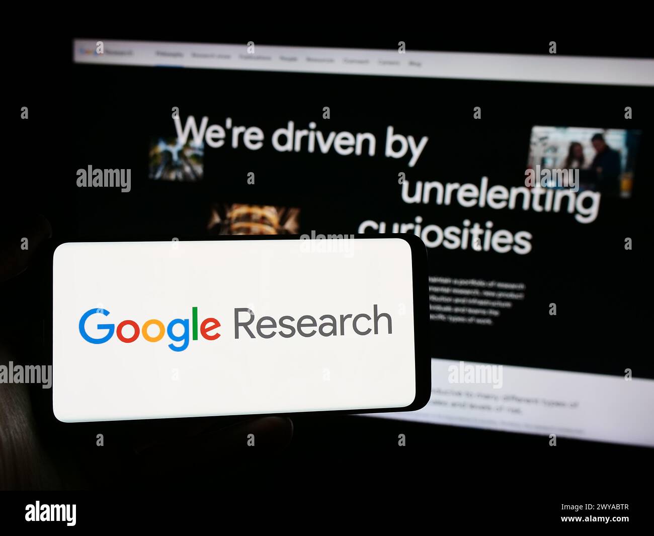 Person holding mobile phone with logo of American technology company Google Research in front of business web page. Focus on phone display. Stock Photo