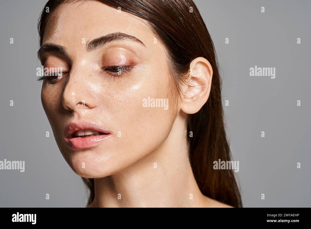 A young Caucasian woman with brown hair exudes elegance and grace in a studio setting. Stock Photo