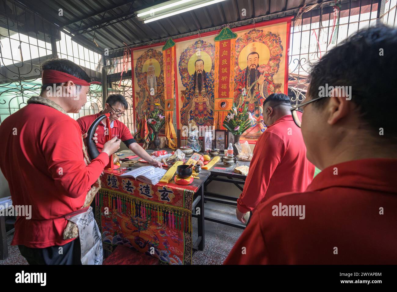 A traditional shaman performing a ritual with offerings to the ancestors on an altar in Donggyue Hall temple Stock Photo