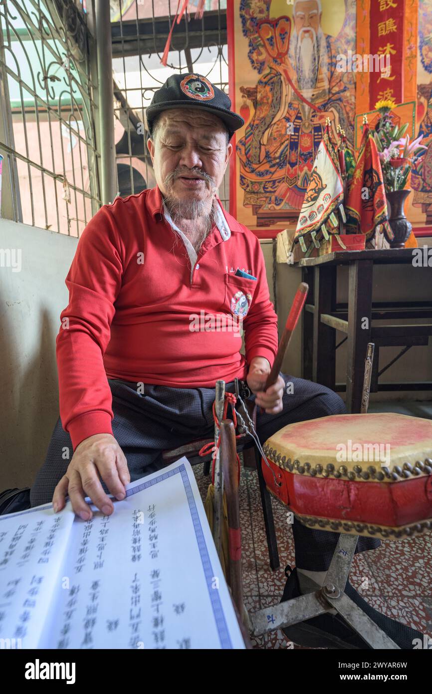 Senior participant playing a drum during a cultural ceremony inside Dongyue Hall temple Stock Photo