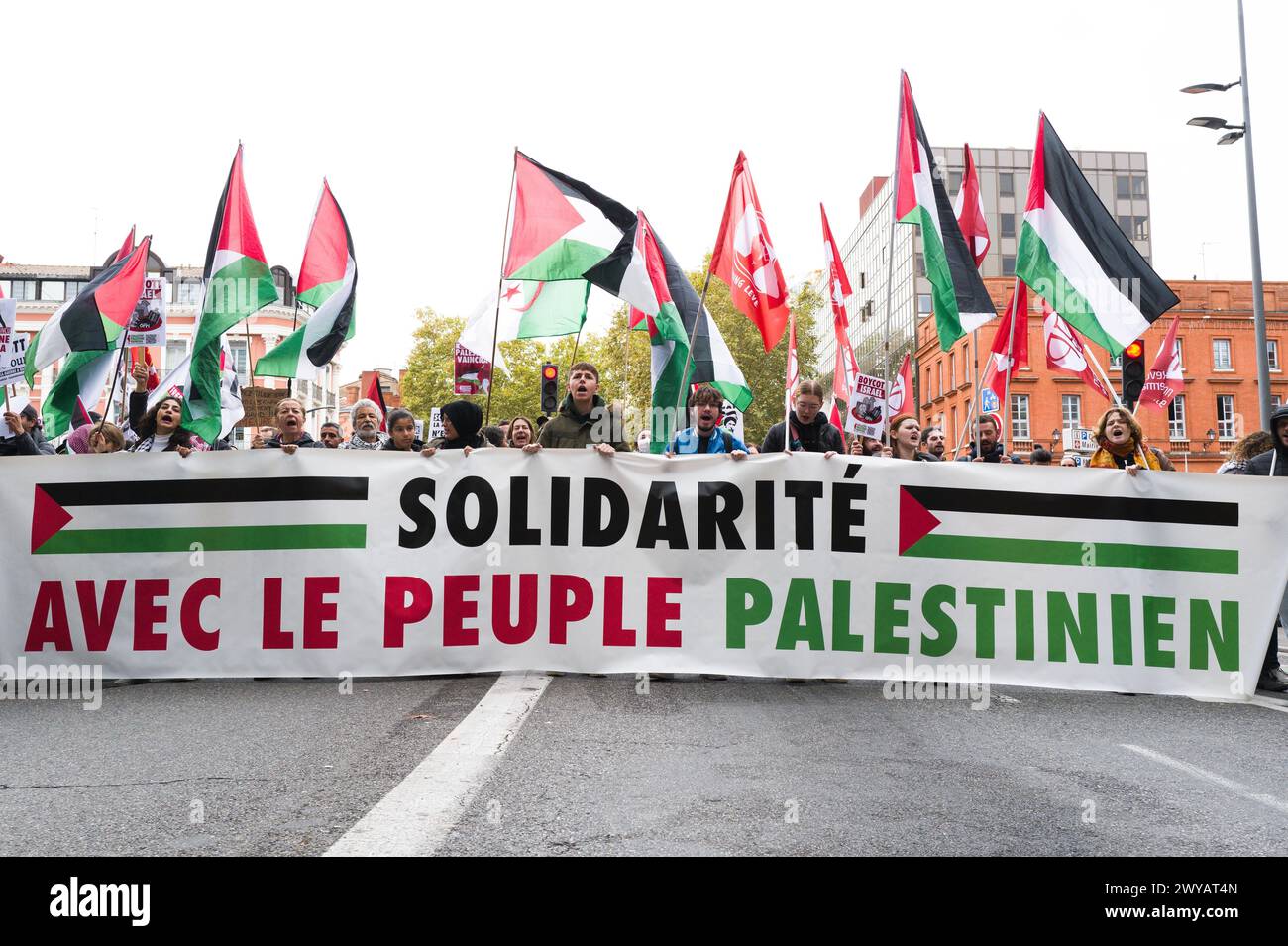 At the start of the demonstration at Jean-Jaures metro station, activists with flags behind the banner, Solidarite avec le peuple palestinien. Stock Photo