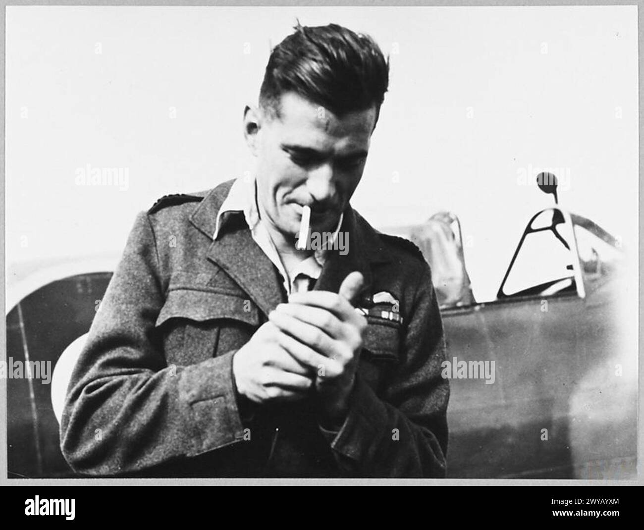 Wing Commander J.E. Johnson of the Royal Air Force lights a cigarette ...