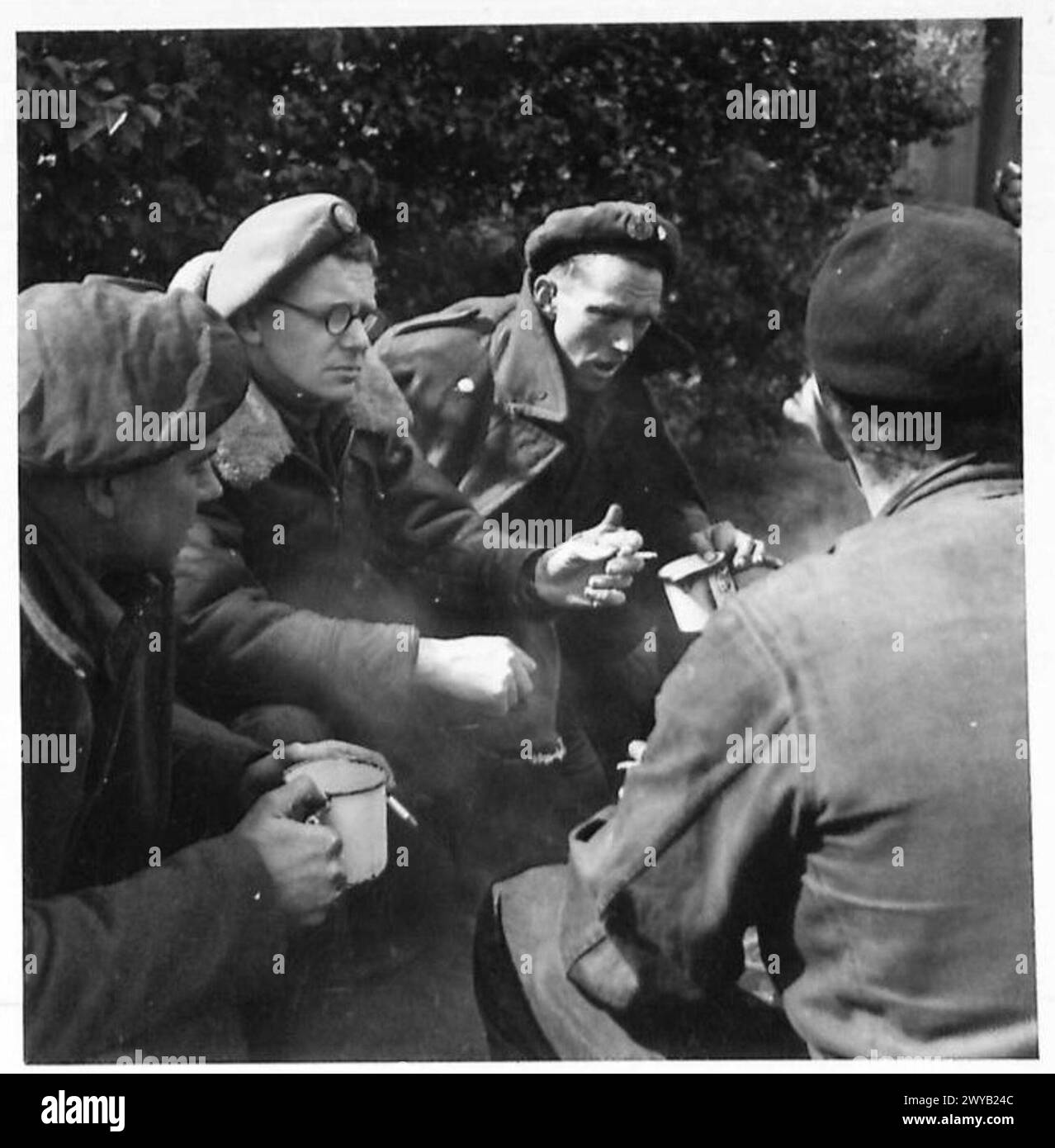 GILES IN GERMANY - Original wartime caption: Giles joins a group of soldiers and partakes of a cup of tea with them. He makes notes of their remarks and uses a lot of them in his cartoons. Photographic negative , British Army, 21st Army Group Stock Photo