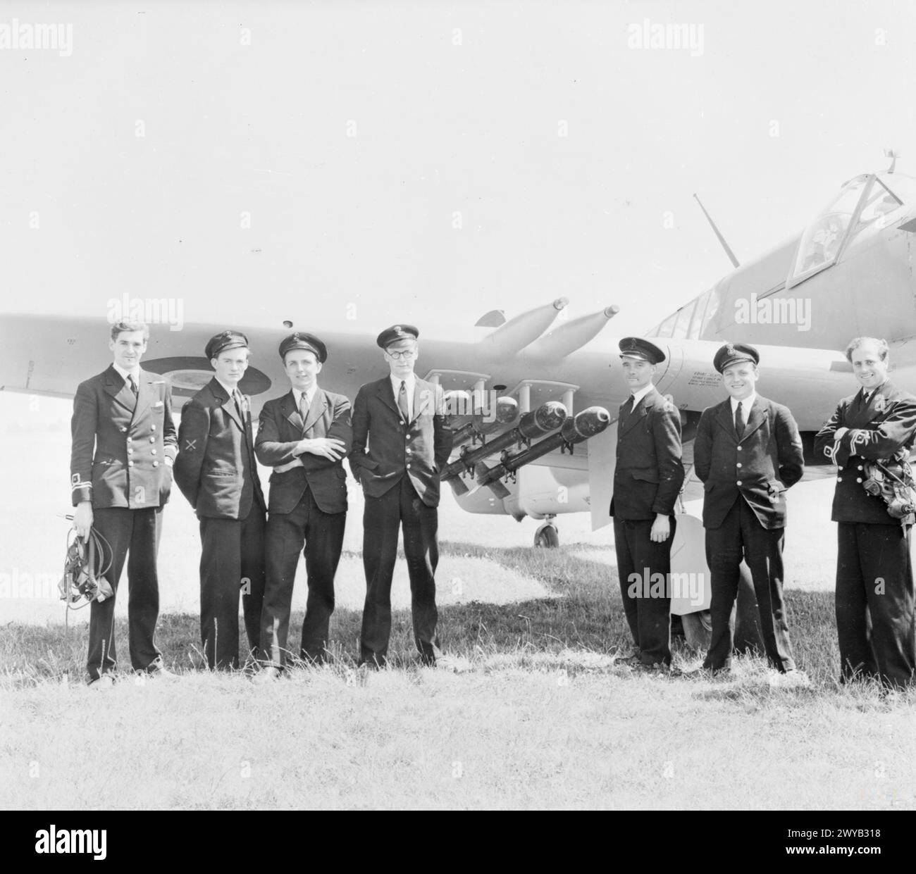 NAVAL FIGHTER ACES TO TOUR AMERICA. JUNE 1945, BEFORE-DEPARTURE PICTURES OF THE NAVAL PILOT, NAVIGATOR AND GROUND CREW OF THE FAIREY FIREFLY TWO-SEATER RECONNAISSANCE PLANE WHICH THEY ARE TAKING TO THE USA FOR PURPOSES OF DEMONSTRATION AND INSTRUCTION. - The Fairey team; pilot, navigator and ground crew. Left to right: Lieut R G Armitage, DFC, RNVR, navigator; AF (O) H Brown; AF (L) S Kirkman; Pilot R M T J Marriott; LAF (E) R Howell; AA4 J F Bunker; Lieut D R Owen Price, DFC, RNVR, Pilot. , Stock Photo