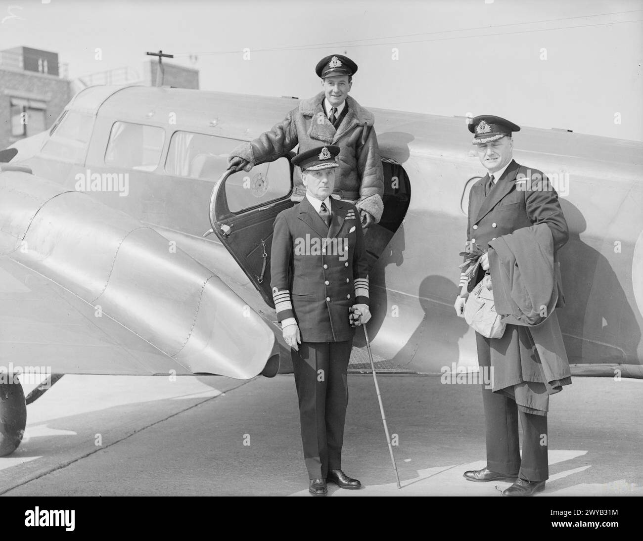 THE FLYING ADMIRAL. 1942, SPEKE AERODROME, LIVERPOOL. THE COMMANDER IN CHIEF WESTERN APPROACHES ADMIRAL SIR PERCY NOBLE, KCB, CVO, FLIES TO MOST EVERY PART OF HIS FAR FLUNG COMMAND. - Admiral Sir Percy Noble, KCB, CVO, about to enter his plane. With him are Captain Whitehorn, RN, and Lieut G C Wilby, RNVR, the Admiral's personal pilot. , Stock Photo