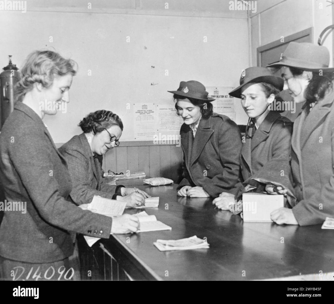 THEY LEARN TO BE LUMBERJILLS: WOMEN'S LAND ARMY FORESTRY TRAINING, CULFORD, SUFFOLK, 1943 - Three new recruits, already in their WLA uniforms, arrive at the training camp at Culford. Miss Ordish (left), the Deputy Superintendent and PT instructor, and Mrs Jackson, Superintendent, receive their ration books and issue their insurance cards before training begins. , Stock Photo