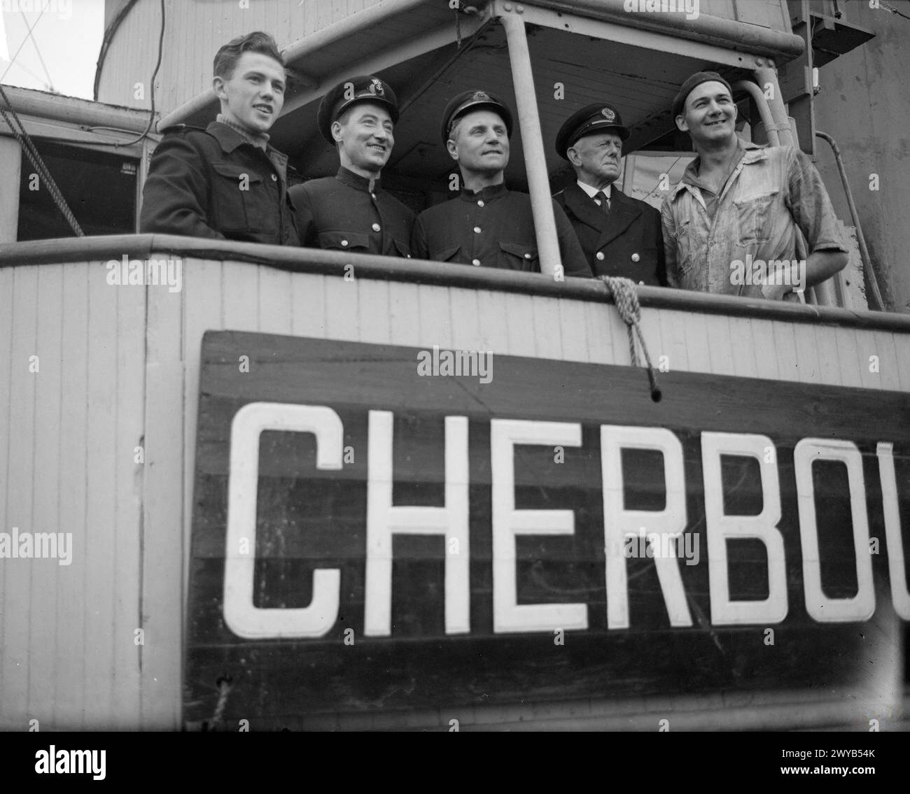 HARBOUR TUG RESCUES GRAIN SHIP. 30 MAY 1944, GREENOCK. MEN OF THE HARBOUR TUG CHERBOURGEOIS III WHICH DASHED OUT INTO THE ATLANTIC TO TOW IN A RUDDERLESS MERCHANT SHIP LADEN WITH GRAIN, AND AFTER TWO DAYS STEAMING AT 5 KNOTS IN A HEAVY SWELL, SHE BROUGHT THE SHIP SAFELY TO HARBOUR. - Left to right: Radio Operator W Blake, of Glasgow; Chief Steward R A Farley, from Sunderland; Captain H Martell, the Skipper from Poole, Chief Officer Robert Reid, from Belfast; and Chief Engineer H G Hall, from Burnley, officers of the CHERBOURGEOIS III. , Stock Photo