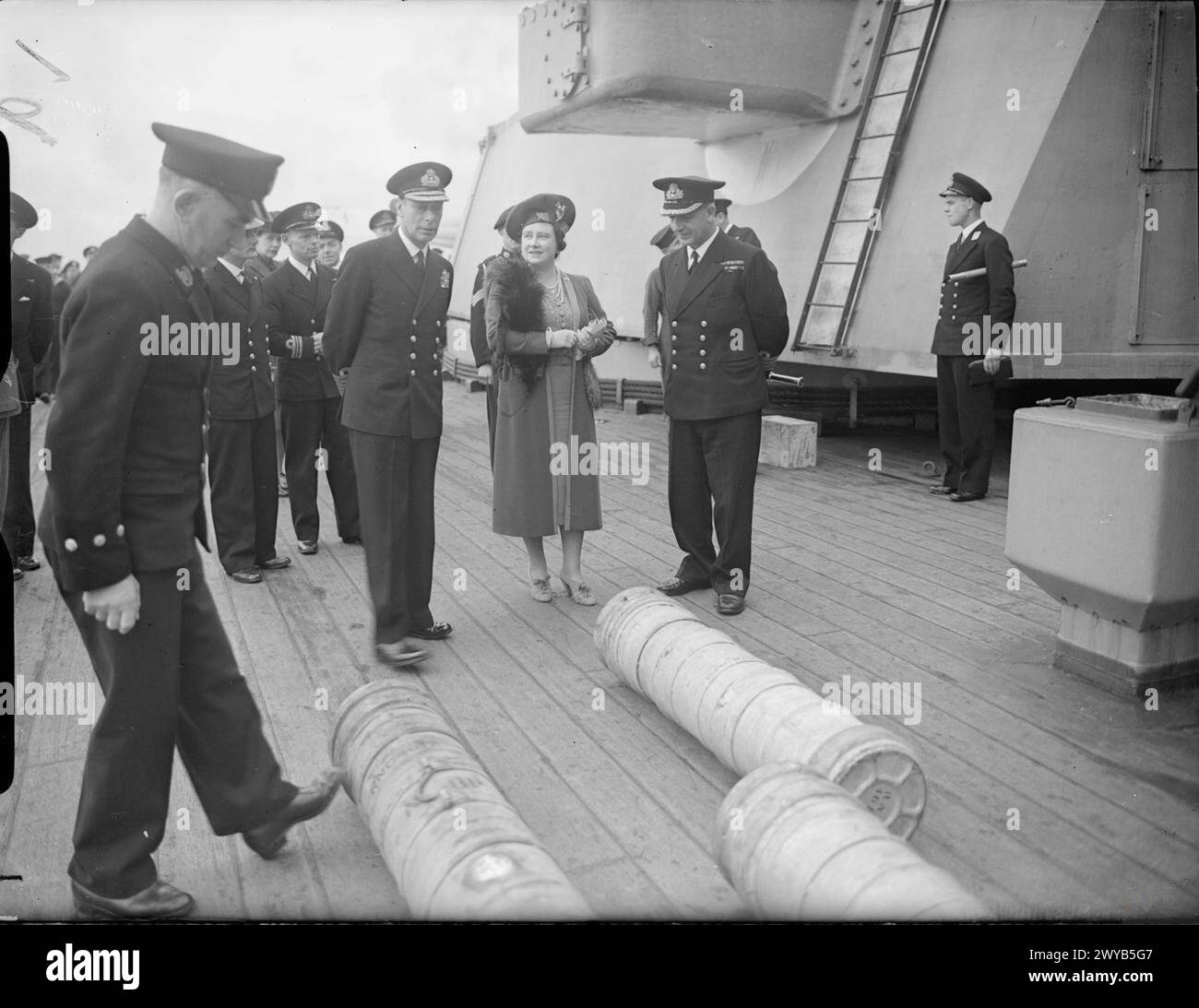 ROYAL VISIT TO HMS KING GEORGE V. 29 OCTOBER 1944, GREENOCK. THE KING AND QUEEN ACCOMPANIED BY PRINCESS ELIZABETH AND PRINCESS MARGARET PAID A FAREWELL VISIT TO THE BATTLESHIP HMS KING GEORGE V BEFORE SHE LEFT TO JOIN BRITAIN'S EAST INDIES FLEET. - The King and Queen with the Commanding Officer of the KING GEORGE V, Captain T E Halsey, DSO, RN, watching 14-inch cordite charges being rolled across the deck. , Stock Photo