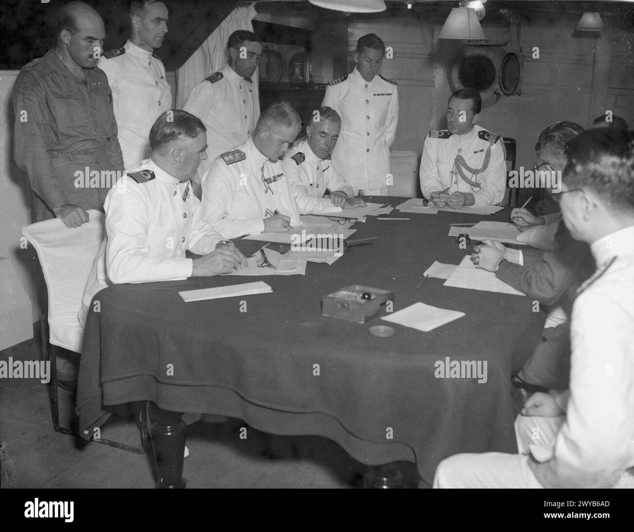 PENANG CONFERENCE ON BOARD HMS NELSON. 28 AUGUST TO 2 SEPTEMBER 1945, ON BOARD THE BRITISH BATTLESHIP HMS NELSON, FLAGSHIP OF VICE ADMIRAL H T C WALKER. DURING THE PENANG SURRENDER AND RE-OCCUPATION NEGOTIATIONS. REAR ADMIRAL UZUNI AND THE JAPANESE GOVERNOR OF PENANG SIGNED FOR THE JAPANESE AFTER WHICH THE DOCUMENTS OF AGREEMENT WERE SIGNED BY VICE ADMIRAL H T C WALKER AT 2115 HOURS ON 1 SEPTEMBER 1945. ROYAL MARINES OF THE BRITISH EAST INDIES FLEET FORMALLY TOOK OVER THE ISLAND ON 3 SEPTEMBER 1945. - Vice Admiral Walker (left, centre) with his staff making the final arrangements (2 September Stock Photo