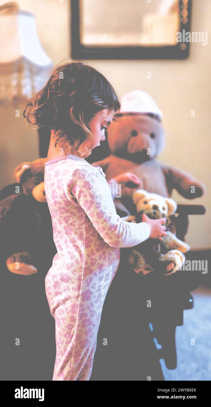 Little girl looking at a teddy bear she's holding Stock Photo - Alamy
