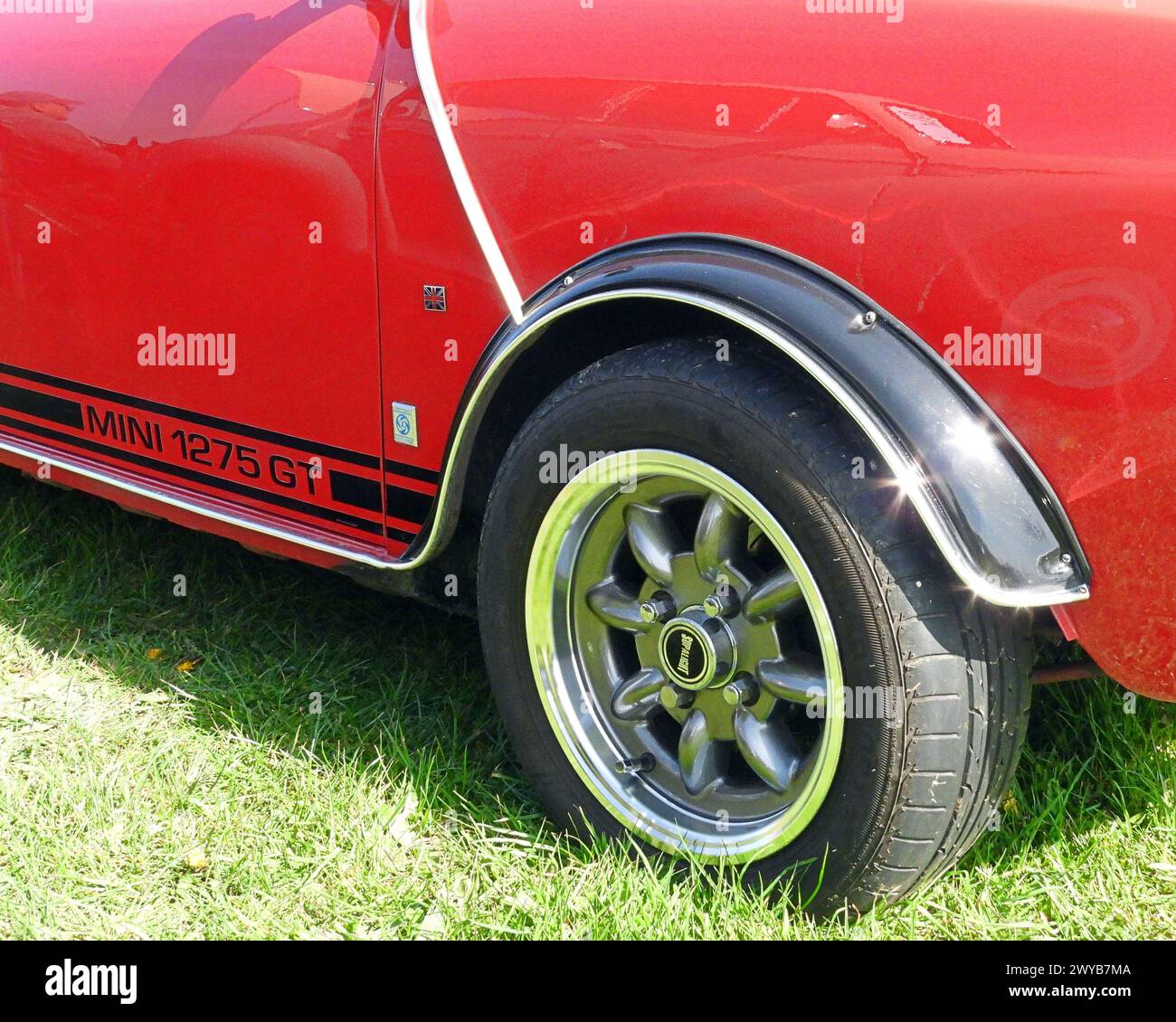 Side view of a classic Mini 1275 GT car in red and showing the front wheel and side trim Stock Photo