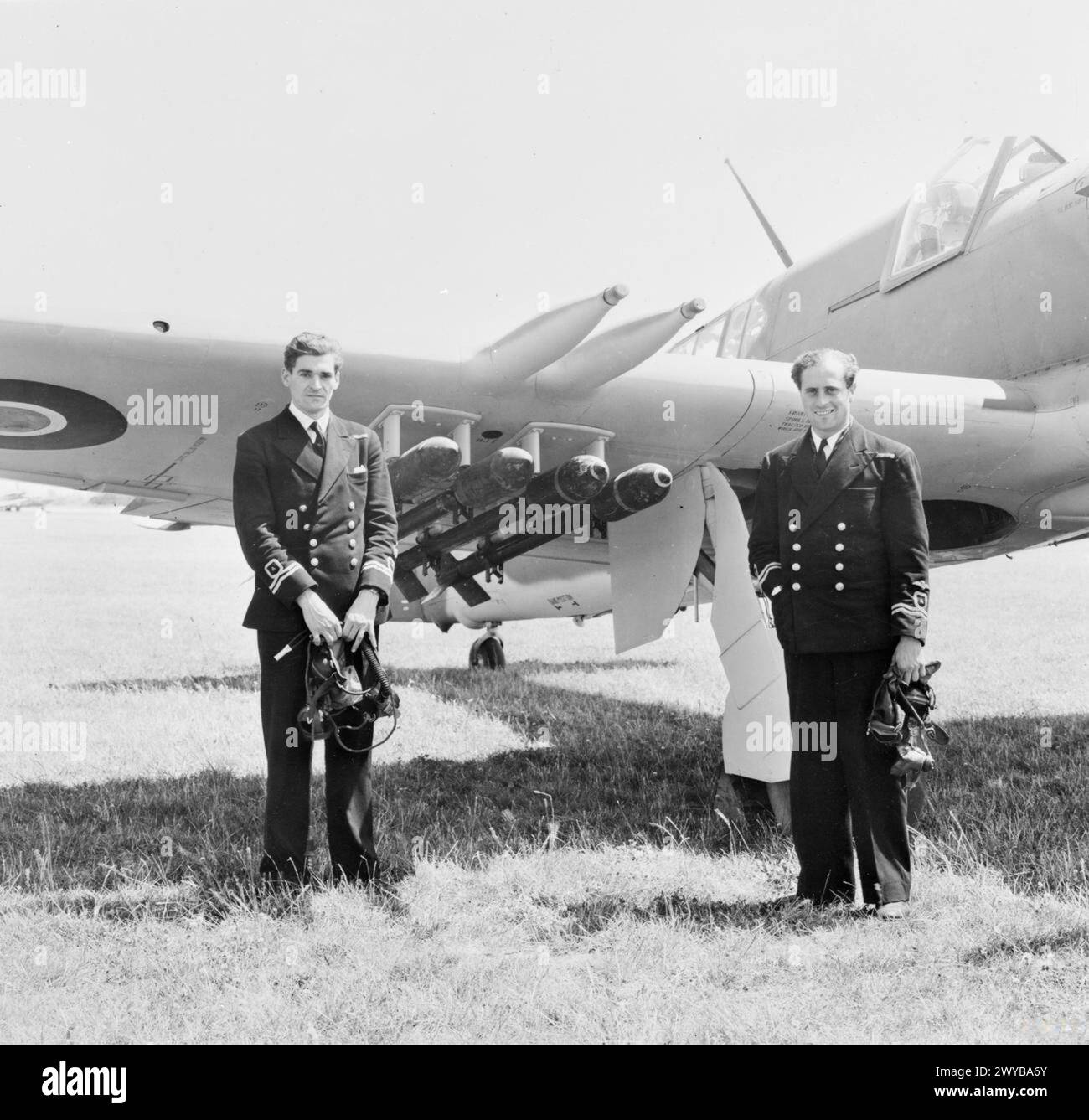 NAVAL FIGHTER ACES TO TOUR AMERICA. JUNE 1945, BEFORE-DEPARTURE PICTURES OF THE NAVAL PILOT, NAVIGATOR AND GROUND CREW OF THE FAIREY FIREFLY TWO-SEATER RECONNAISSANCE PLANE WHICH THEY ARE TAKING TO THE USA FOR PURPOSES OF DEMONSTRATION AND INSTRUCTION. - Lieut R G Armitage, DFC, RNVR, navigator (left) and Lieut D R Owen Price, DFC, RNVR, the pilot, with the plane. , Stock Photo