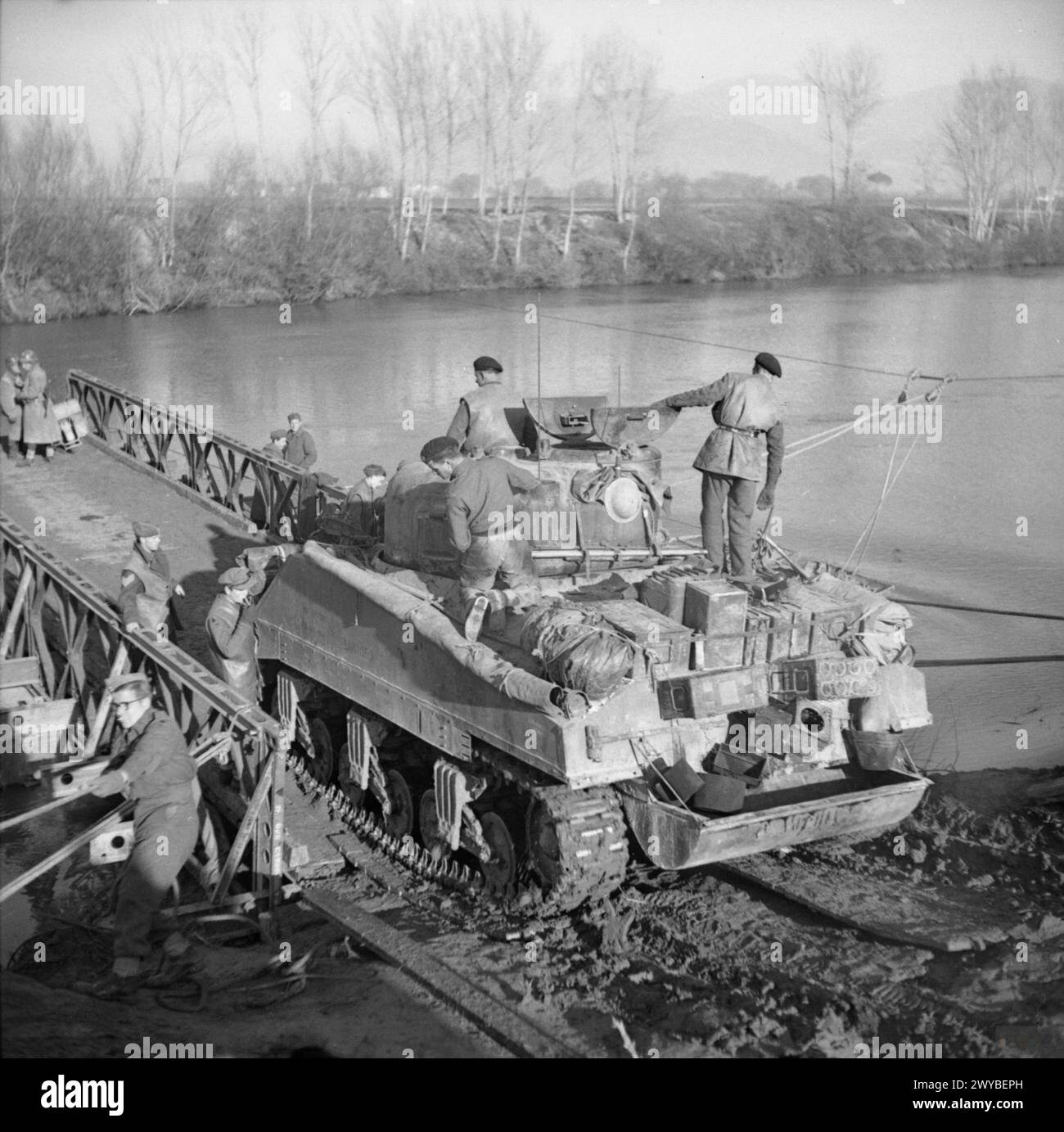A British Army Sherman tank is loaded onto a raft for transport across ...