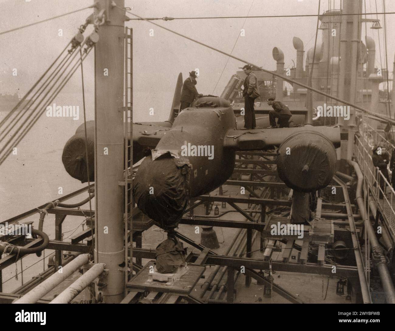 UNITED STATES ARMY AIR FORCES (USAAF) IN BRITAIN, 1942-1945 - US Personnel unload a wrapped P-61 Black Widow at Liverpool docks.Image stamped on reverse: 'Associated Press.' [stamp], 'Not to be published [no date].' [stamp], 'Passed & censored 1 Apr 1944.' [stamp], 'Passed for publication 4 Jun 1945.' [stamp], '314297.' [censor no].Printed caption on reverse: 'The 'Black Widow' arrives in EnglandAssociated Press Photo Shows:- 'Black Widows' on board the ship which brought them safely from U.S. to this country ready for unloading.'Handwritten caption on reverse: '266416.' , Stock Photo