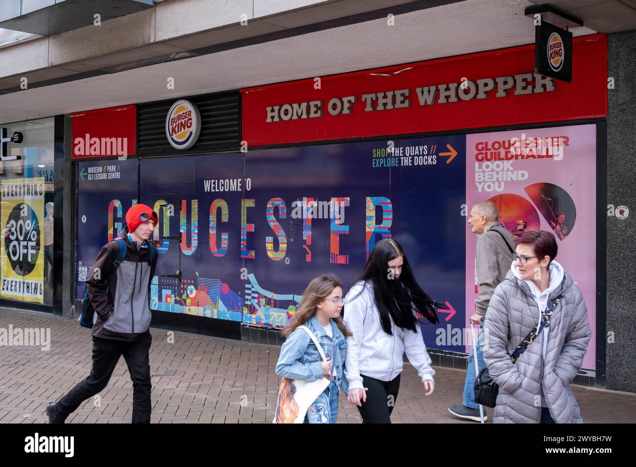 Welcome to Gloucester hoarding on the exterior of the closed down Burger King fast food restaurant, another example of the decline of the UK high street on 2nd April 2024 in Gloucester, United Kingdom. Gloucester city centre is an example of the decline of the UK high street and what some local people are calling a ‘dying city’ as more big name retailers move out and retail spaces close down, having an affect on jobs in the area. Several contributing factors are aligning to result in declining high streets, including the cost of living crisis squeeze on household incomes due to inflation and t Stock Photo