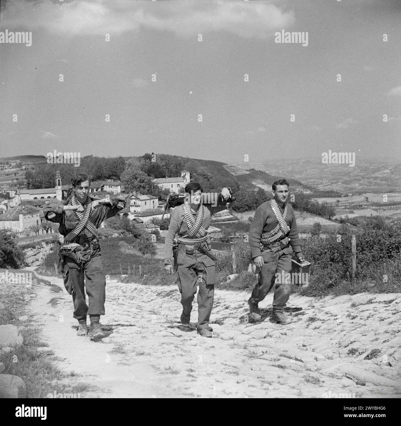 BRITISH SPECIAL FORCES IN ITALY, 1945 - Three heavily armed members of No 2 SAS Regiment, draped with ammunition belts and each carrying components of a Vickers heavy machine gun, climb a mountain path as they go out on an operation to assist Italian partisans in the Castino area of northern Italy. , British Army, Special Air Service Stock Photo