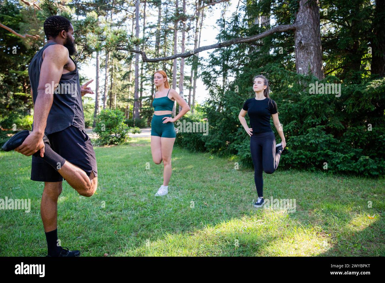 Three people are stretching in a park during a workout together, healthy lifestyle. Stock Photo