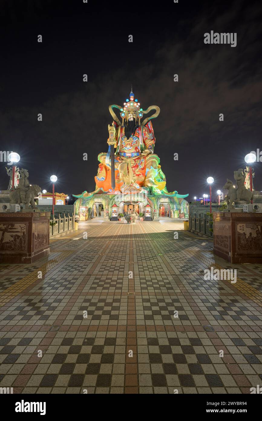 A dazzling display of illuminated lights over an adorned bridge flanked by mythological statues leading to Zuoying Yuandi Temple, set against the darkness of night Stock Photo