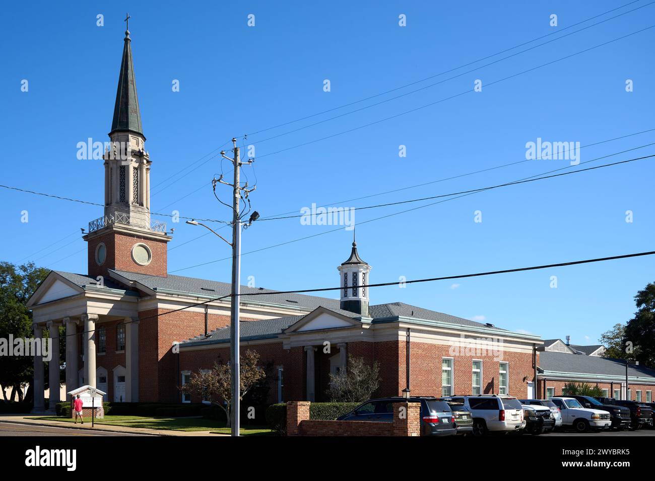 The First Presbyterian Church of Pensacola rises, a beacon of faith with a red-brick embrace, reaching for the heavens through Pensacola's serene blue Stock Photo