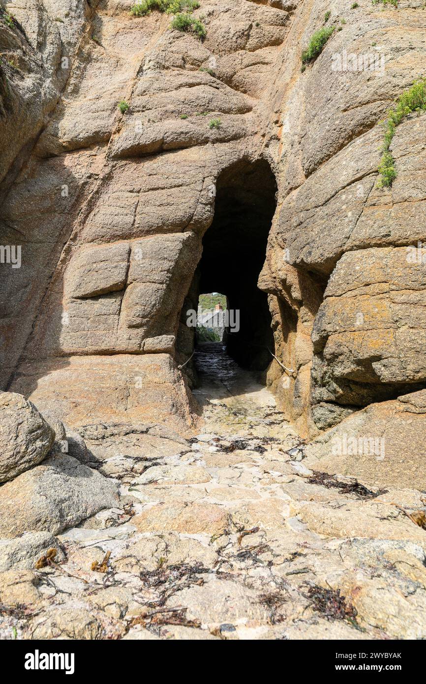 A gap in the rocks or a rock arch or tunnel at Porthgwarra, Cornwall, South West England, UK Stock Photo