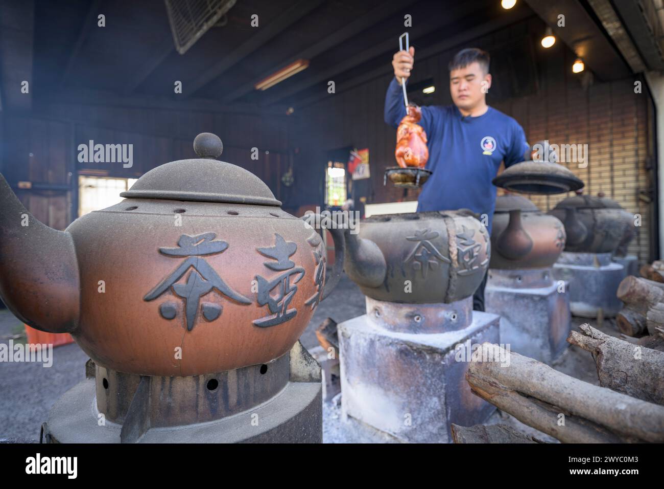 A man cooking a chicken using traditional clay pots over a wood fire Stock Photo