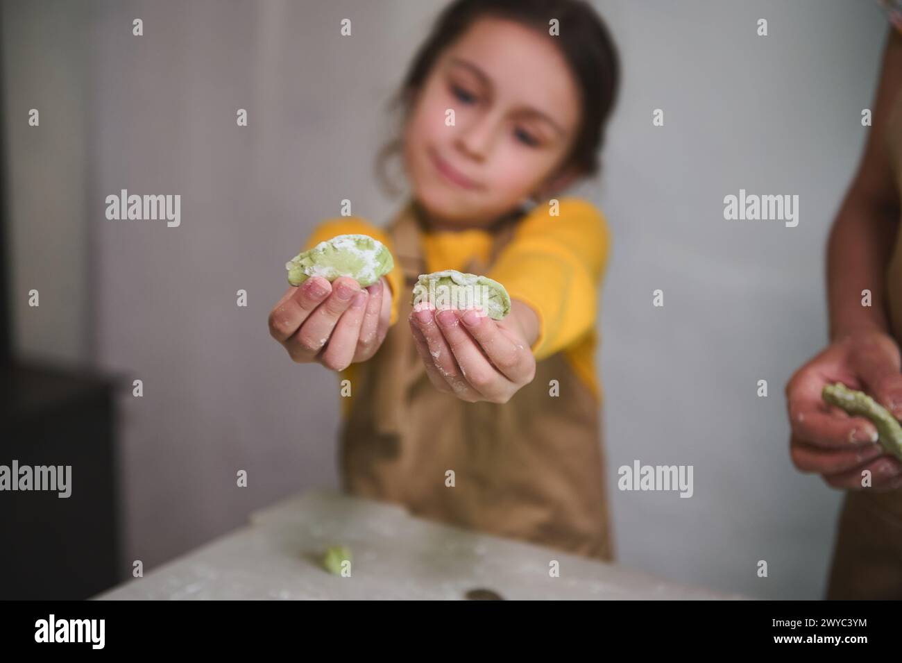Details on two molded homemade dumplings in child girl's hands. Kids learning cooking during culinary masterclass. Childhood. Kids education and enter Stock Photo