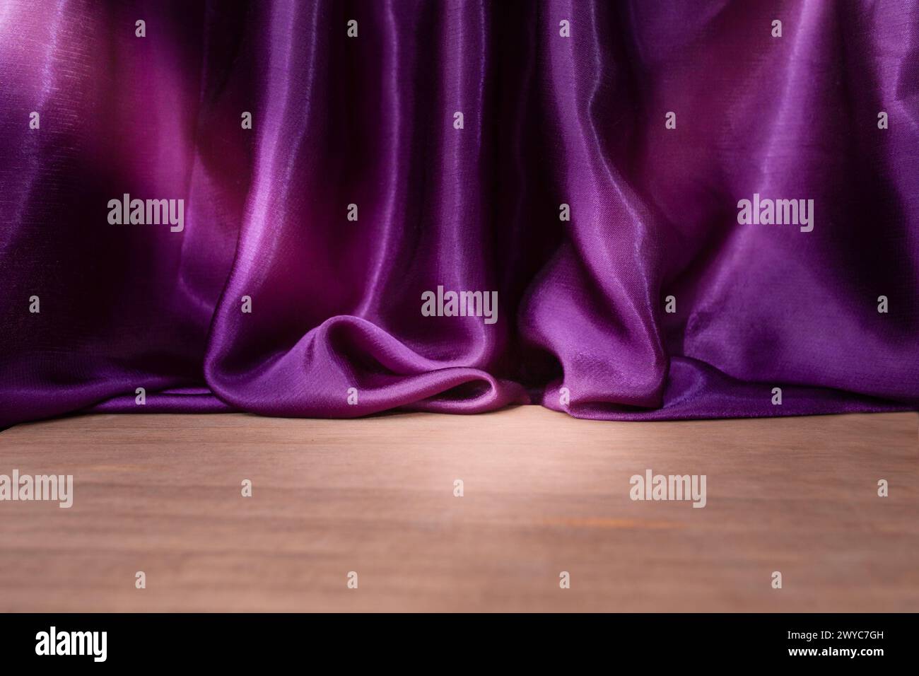 Empty wooden floor with Elegant wavy purple satin cloth curtains, defocused in the background, product placement backdrop Stock Photo