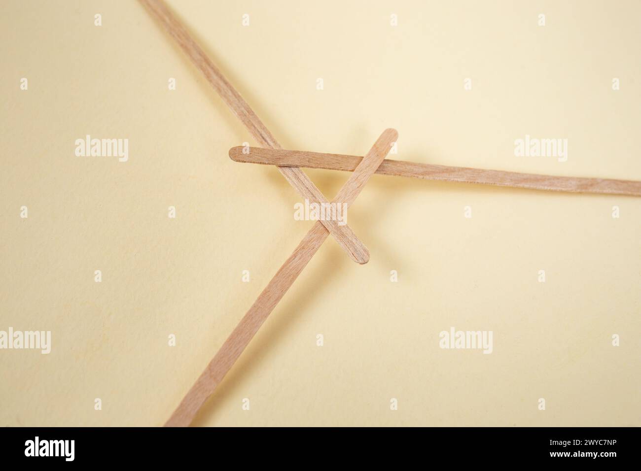 Bamboo wooden sticks demonstrating a reciprocal frame structure, on beige Stock Photo