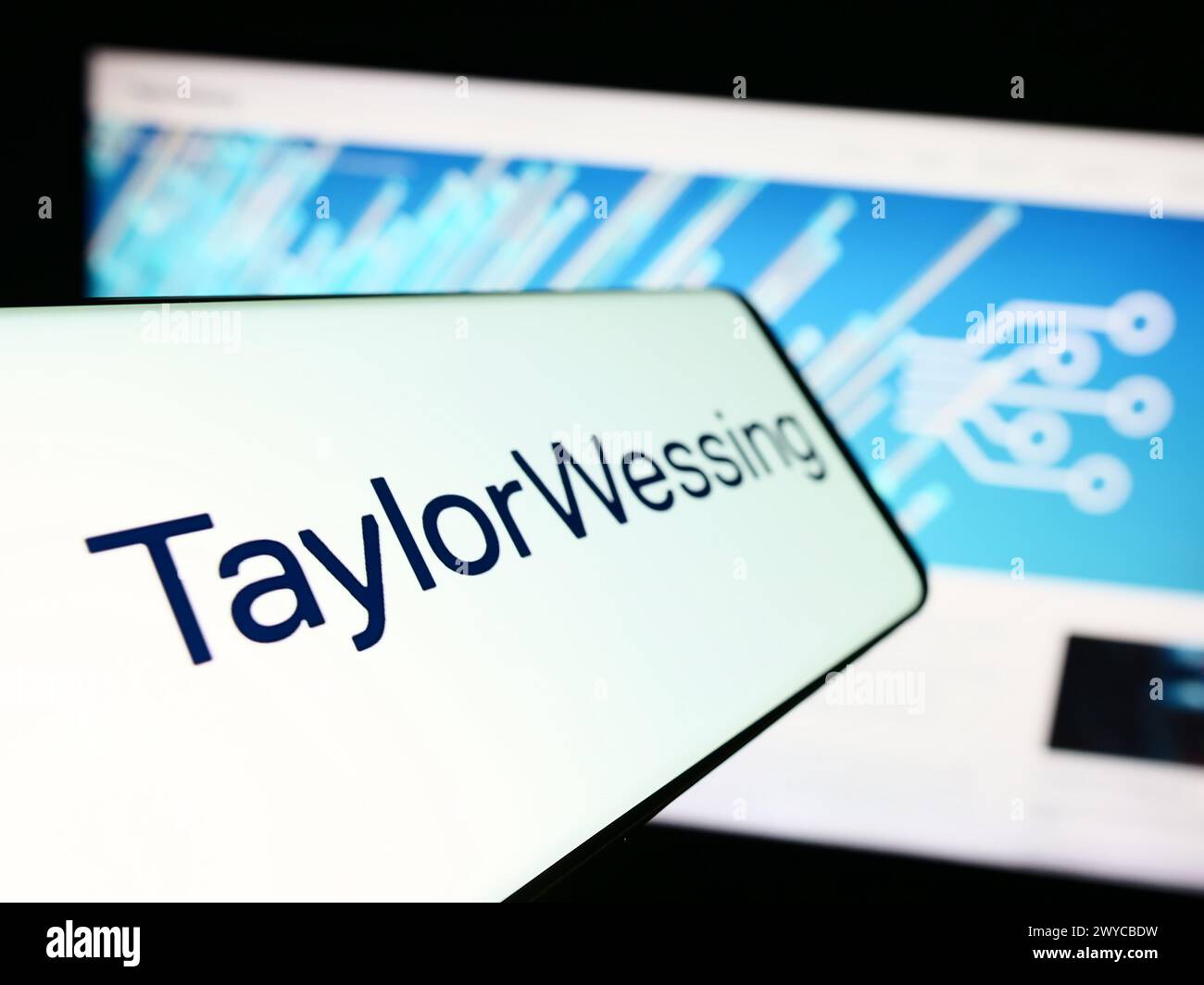 Smartphone with logo of international law company Taylor Wessing LLP in front of business website. Focus on left of phone display. Stock Photo