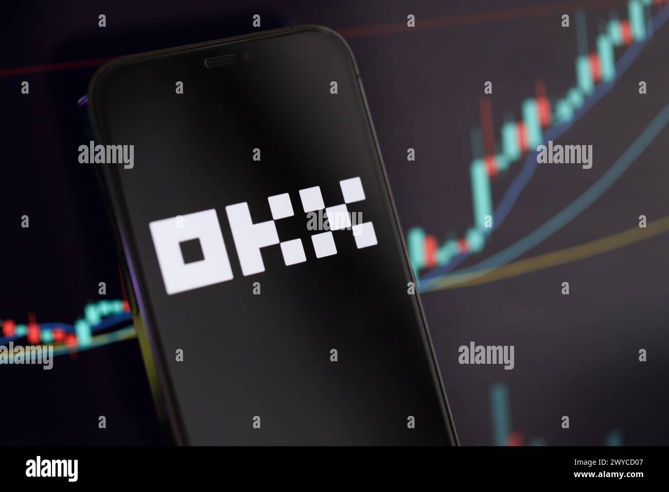 KYIV, UKRAINE - MARCH 15, 2024 OKX logo on iPhone display screen and crypto currency value charts. Cryptocurrency exchange portal Stock Photo