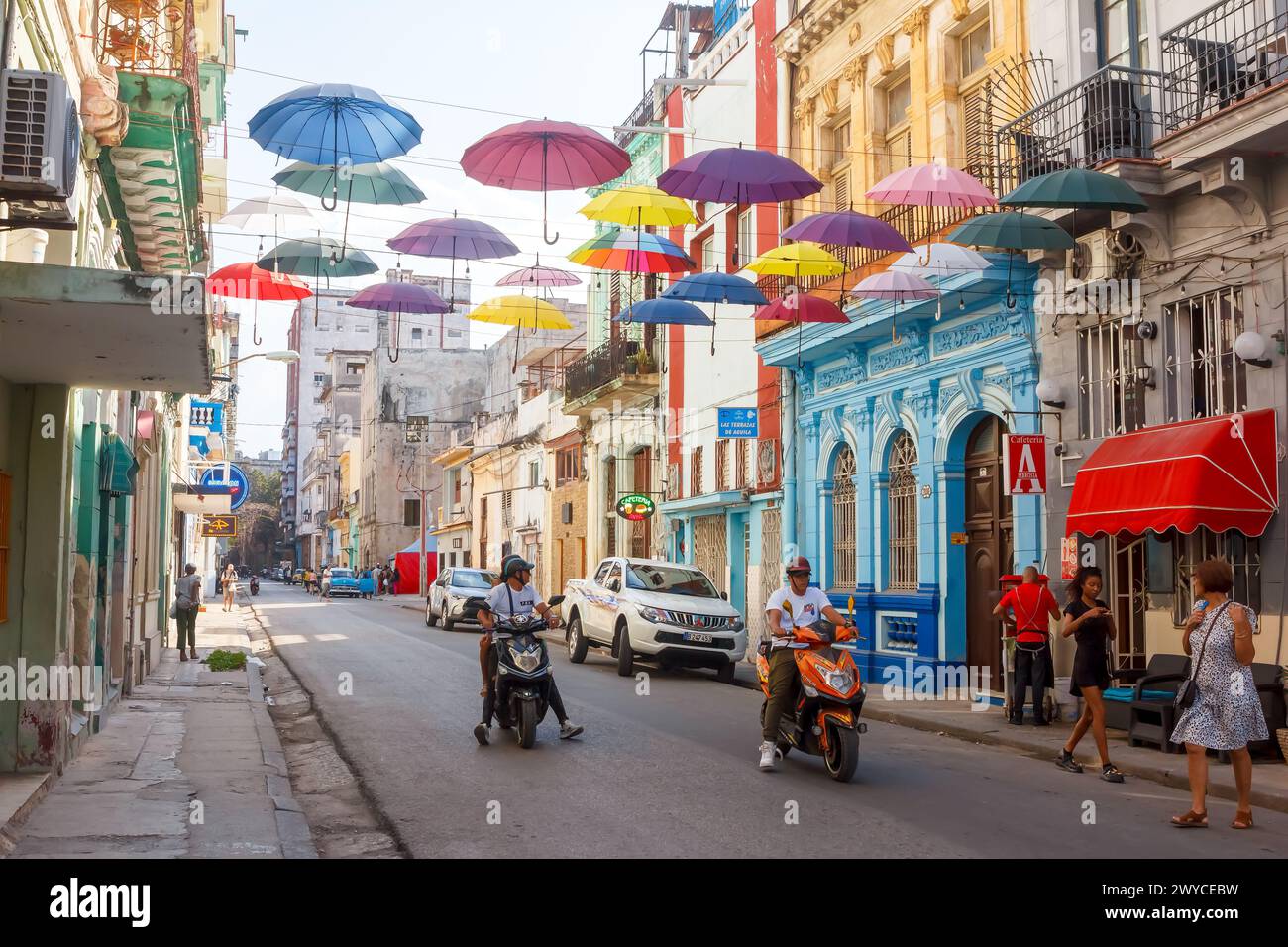 Cuban people driving e-bike by street decoration with umbrellas in Havana, Cuba Stock Photo