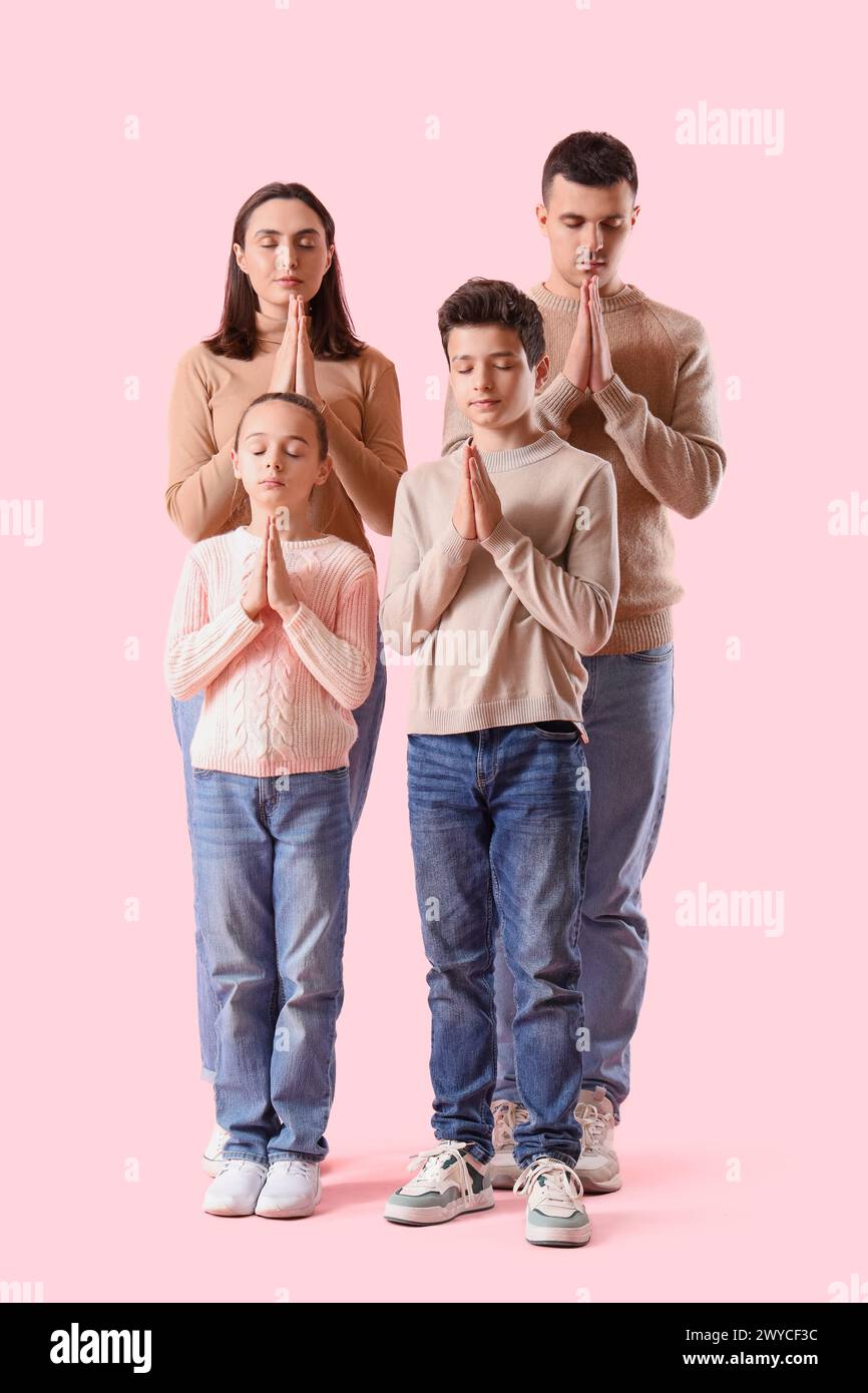 Family praying together on pink background Stock Photo