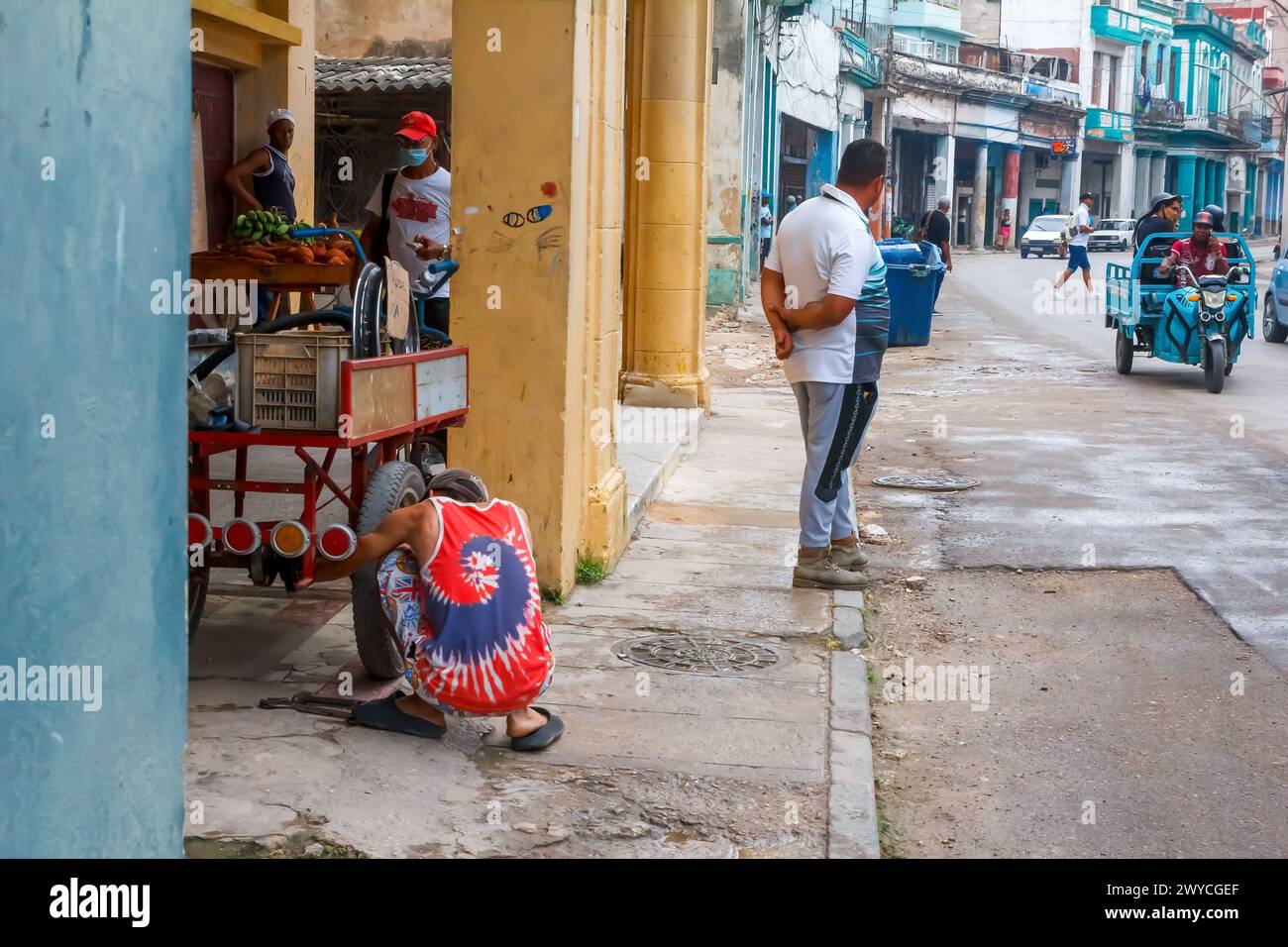 cuban man repairing a wheel of a rustic cart in Havana, Cuba Stock Photo